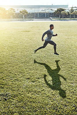 Buy stock photo Full length shot of a handsome and athletic young man running across an open field