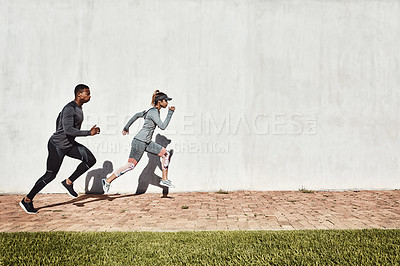 Buy stock photo Full length shot of two young and athletic young people running on a path through the park