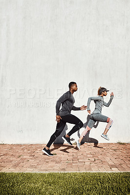 Buy stock photo Full length shot of two young and athletic young people running on a path through the park