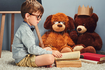 Buy stock photo Studio shot of a smart little boy reading a book to his teddy bears against a gray background