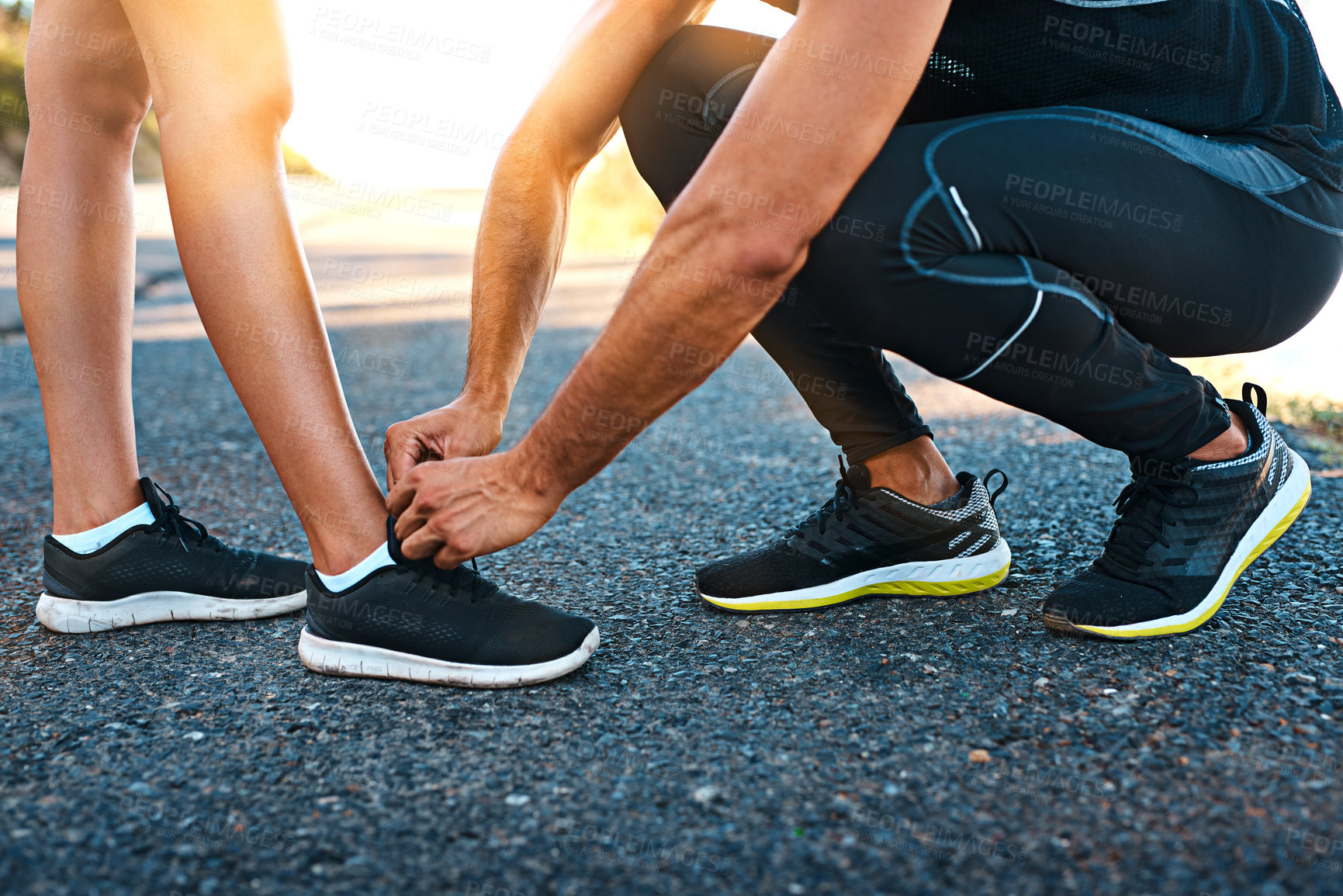 Buy stock photo Cropped shot of an unrecognizable young man typing his girlfriend's laces while out for a run