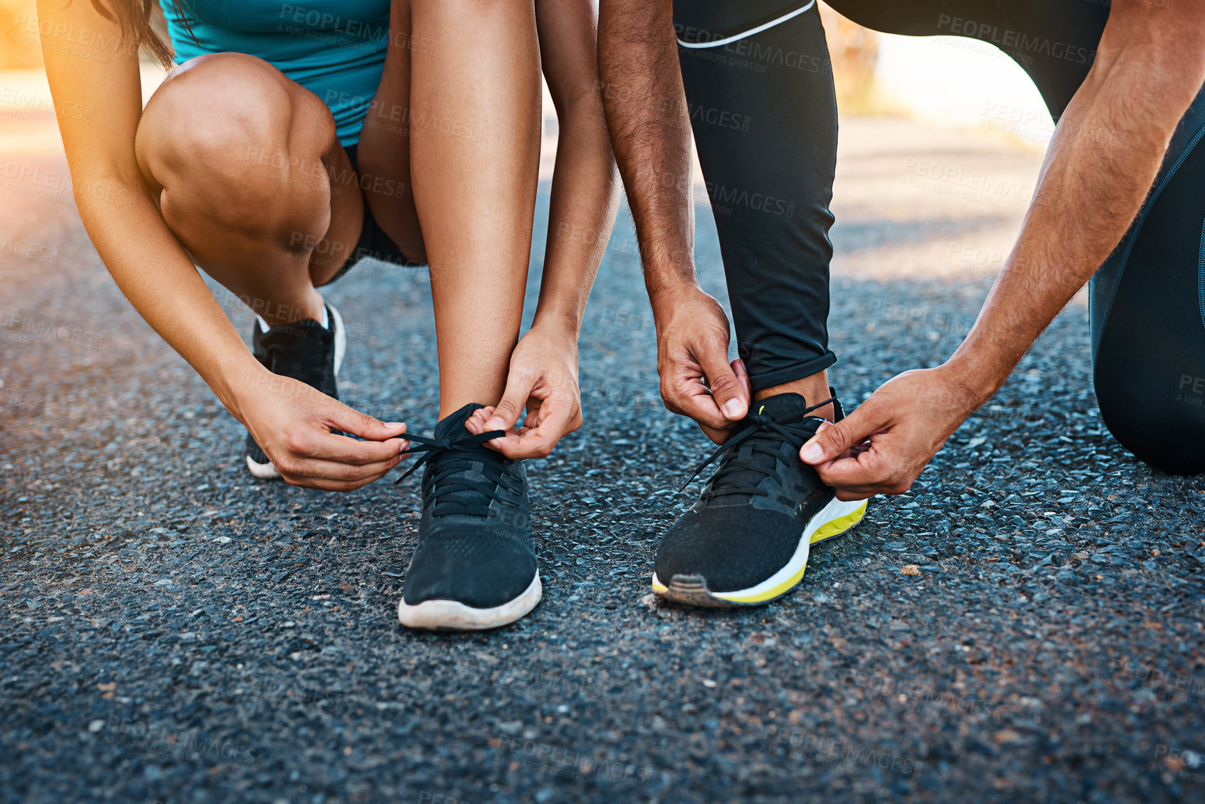 Buy stock photo Cropped shot of an unrecognizable young couple tying their shoelaces while out for a run