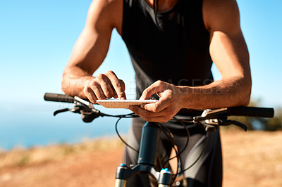Buy stock photo Cropped shot of an unrecognizable man using his cellphone while out for a ride on his mountain bike