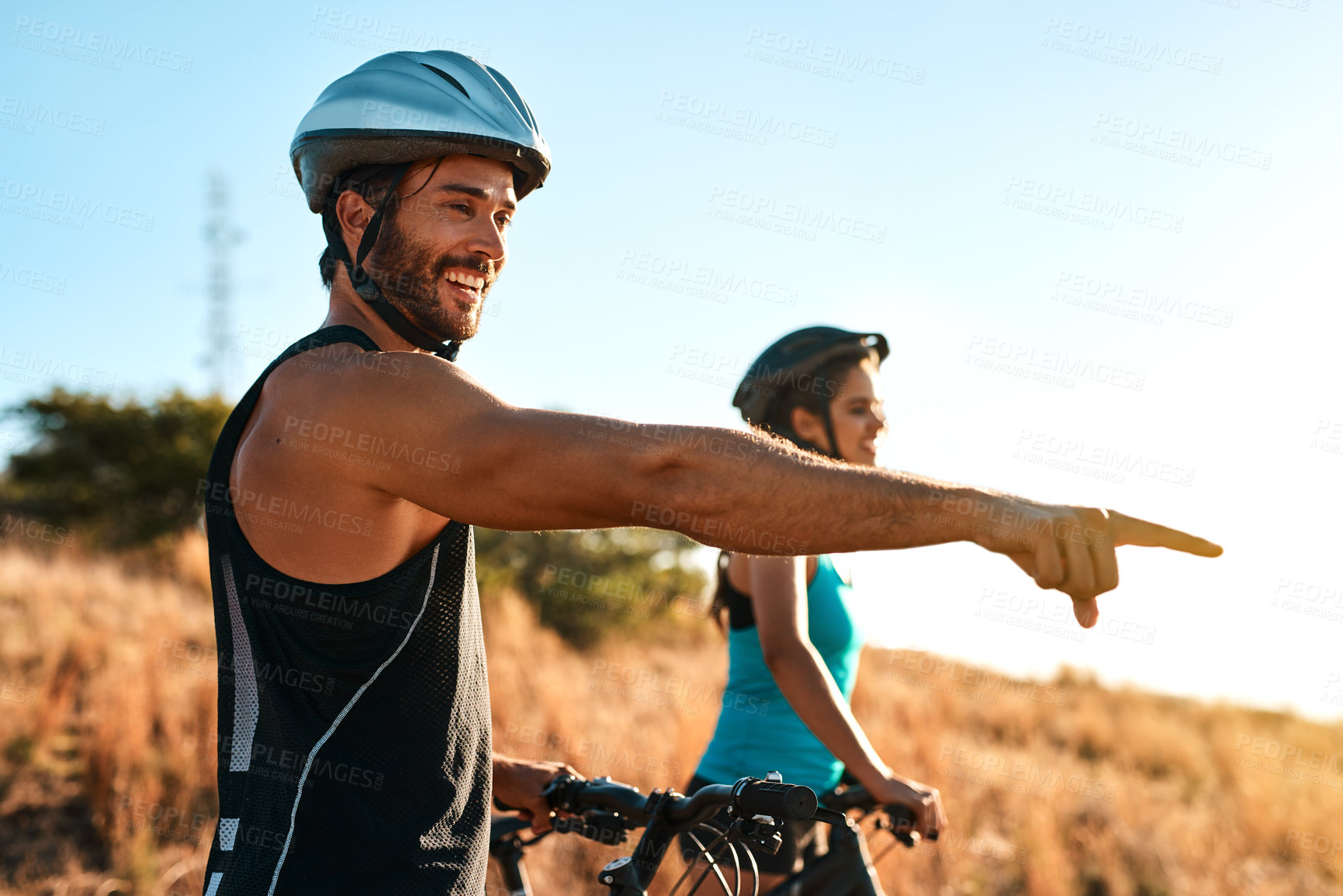 Buy stock photo Happy couple, pointing and cycling in the mountains for fitness and exercise together. Bike, wellness and young man with woman outdoor for adventure, sports or happiness of freedom on blue sky mockup