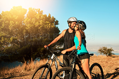 Buy stock photo Cropped shot of a happy young couple kissing while out mountain biking together