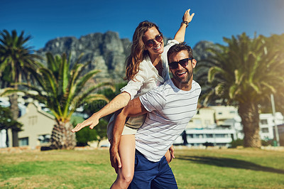 Buy stock photo Cropped portrait of a happy young couple enjoying a piggyback ride at the beach