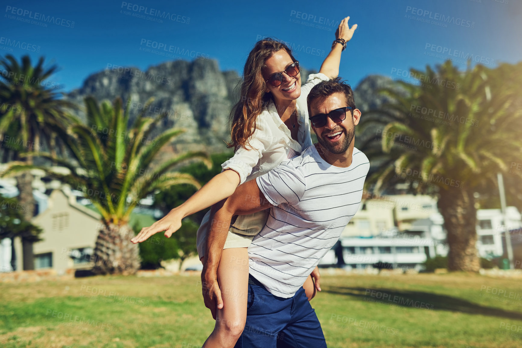 Buy stock photo Cropped portrait of a happy young couple enjoying a piggyback ride at the beach