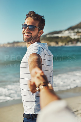 Buy stock photo Cropped shot of a young man holding his girlfriend’s hand and leading the way at the beach