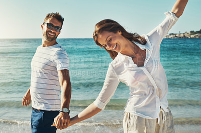 Buy stock photo Cropped shot of a happy young couple running along the beach