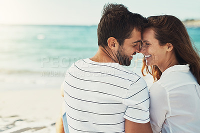 Buy stock photo Rearview shot of a young couple kissing on a summer’s day at the beach