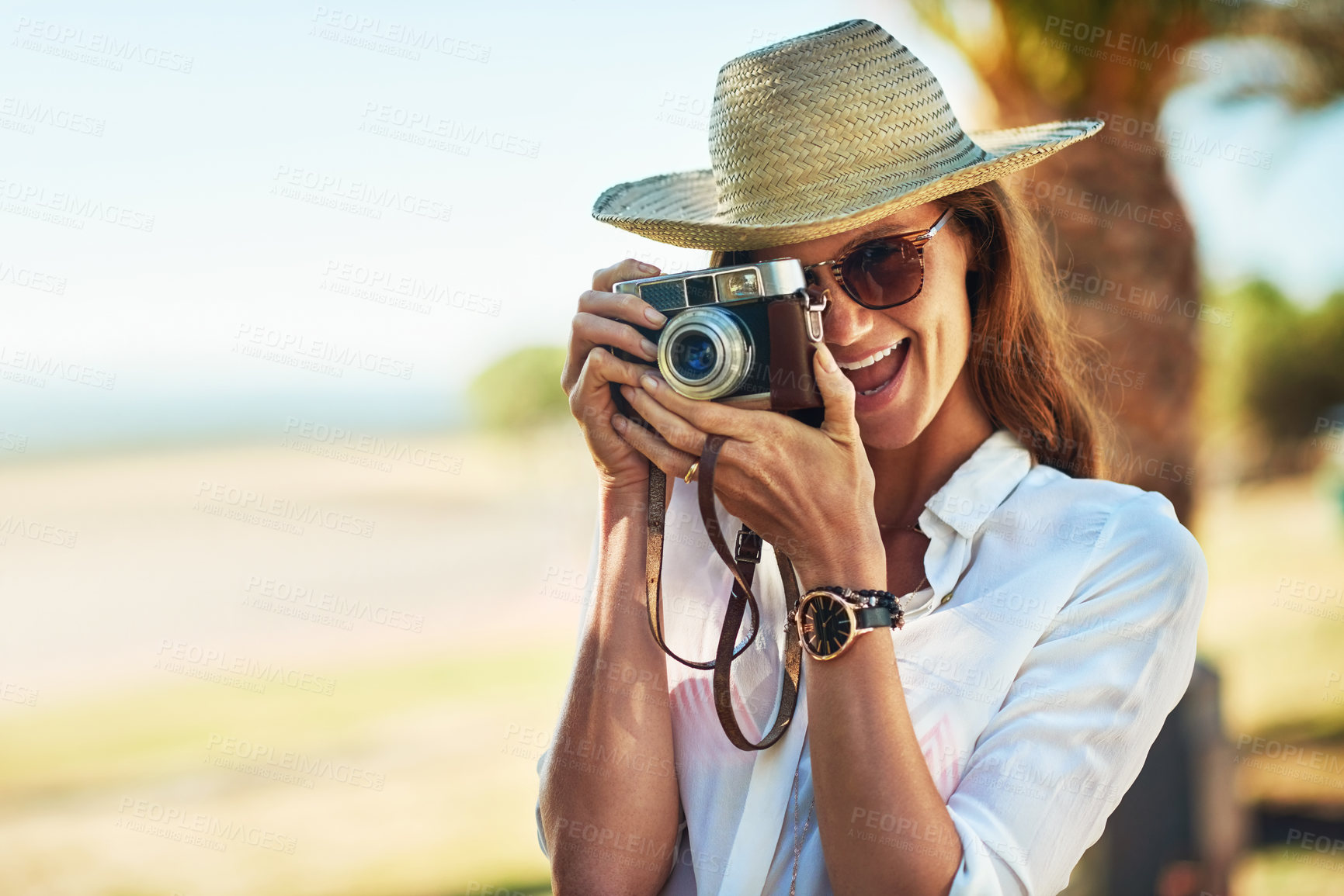 Buy stock photo Cropped shot of an attractive young woman using a camera on a summer’s day outdoors