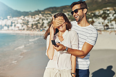 Buy stock photo Cropped shot of a young man proposing to his girlfriend at the beach on a summer’s day