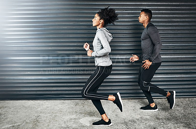 Buy stock photo Shot of a sporty young couple running against a grey background