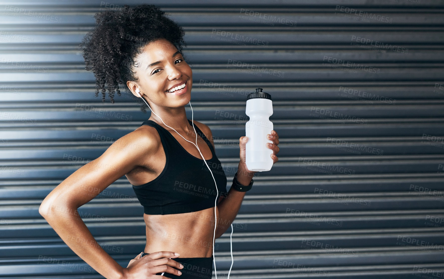 Buy stock photo Portrait of a sporty young woman drinking water while exercising against a grey background