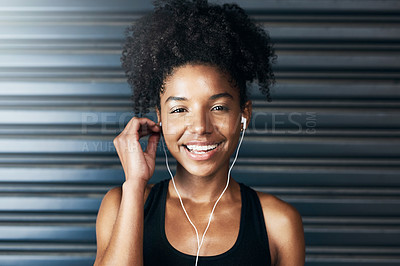 Buy stock photo Portrait of a sporty young woman listening to music while exercising against a grey background