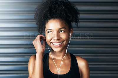 Buy stock photo Shot of a sporty young woman listening to music while exercising against a grey background