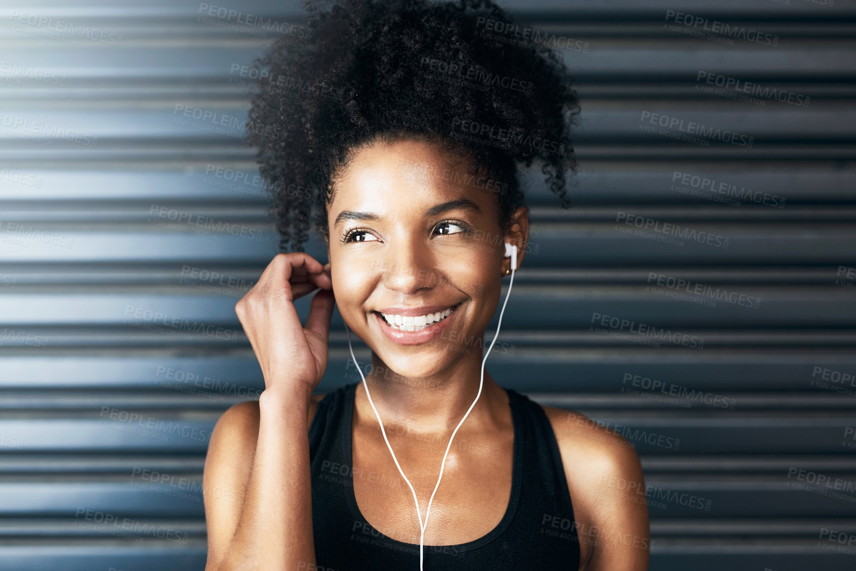 Buy stock photo Shot of a sporty young woman listening to music while exercising against a grey background