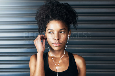 Buy stock photo Shot of a sporty young woman listening to music while exercising against a grey background