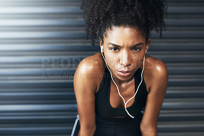 Buy stock photo Portrait of a sporty young woman taking a break while exercising against a grey background