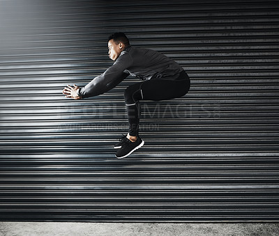 Buy stock photo Shot of a sporty young man jumping against a grey background
