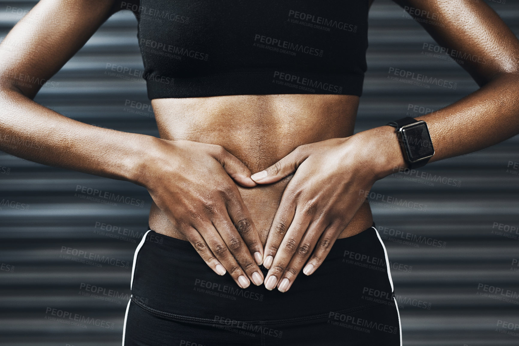 Buy stock photo Closeup shot of an sporty woman making a heart shape with her hands on her stomach against a grey background