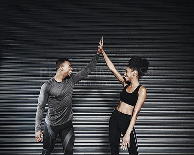 Buy stock photo Shot of a sporty young couple giving each other a high five against a grey background