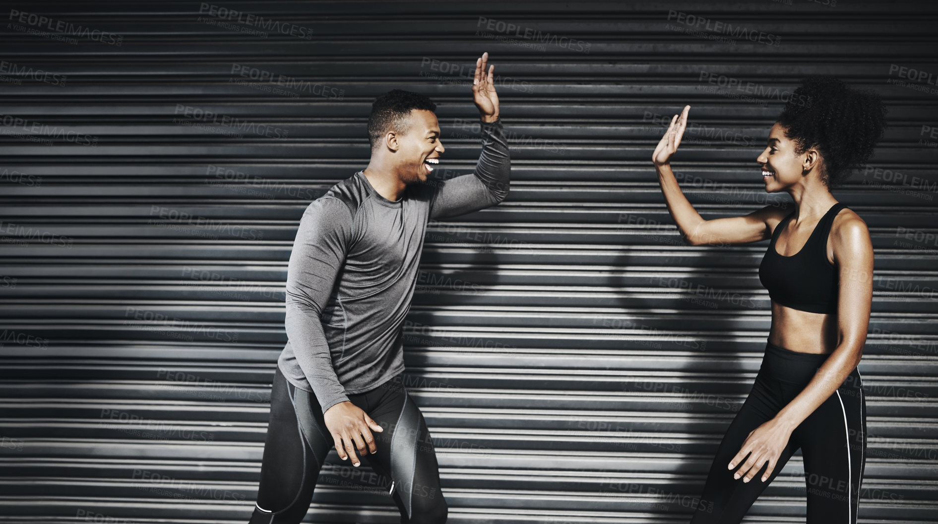 Buy stock photo Shot of a sporty young couple giving each other a high five against a grey background