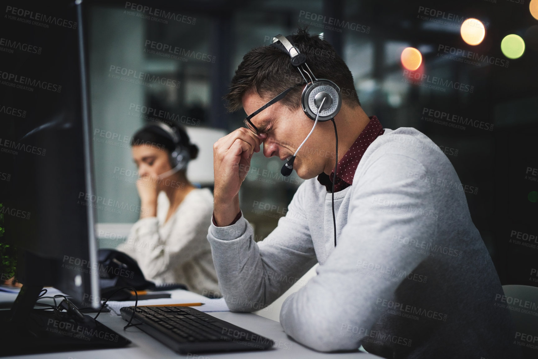 Buy stock photo Cropped shot of a handsome young businessman looking stressed while working late in a call center