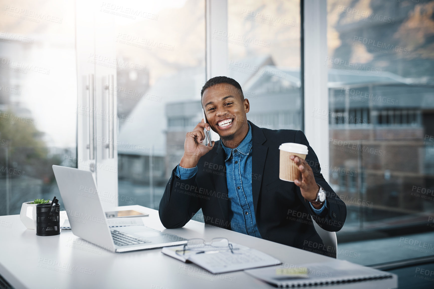 Buy stock photo Shot of a handsome young businessman talking on a cellphone while working in an office