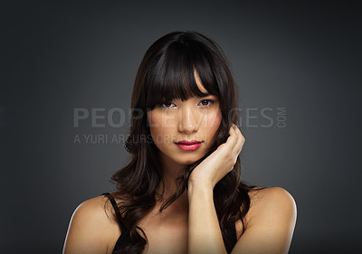 Buy stock photo Studio shot of a beautiful young woman posing with her hand on her face against a dark background