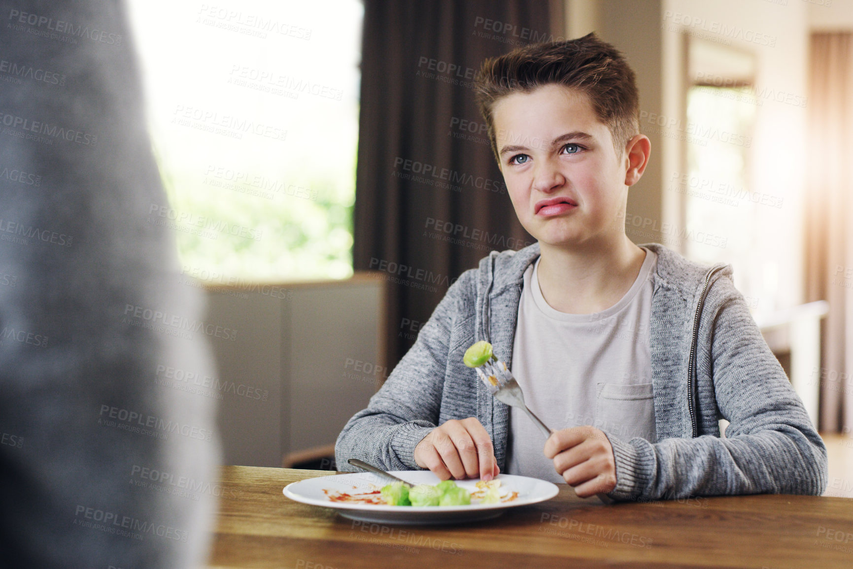 Buy stock photo Shot of a young boy refusing to eat his brussels sprouts at home