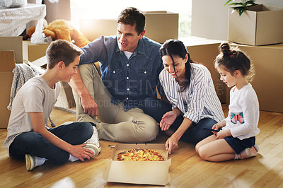 Buy stock photo Shot of a happy young family having pizza together in their new home