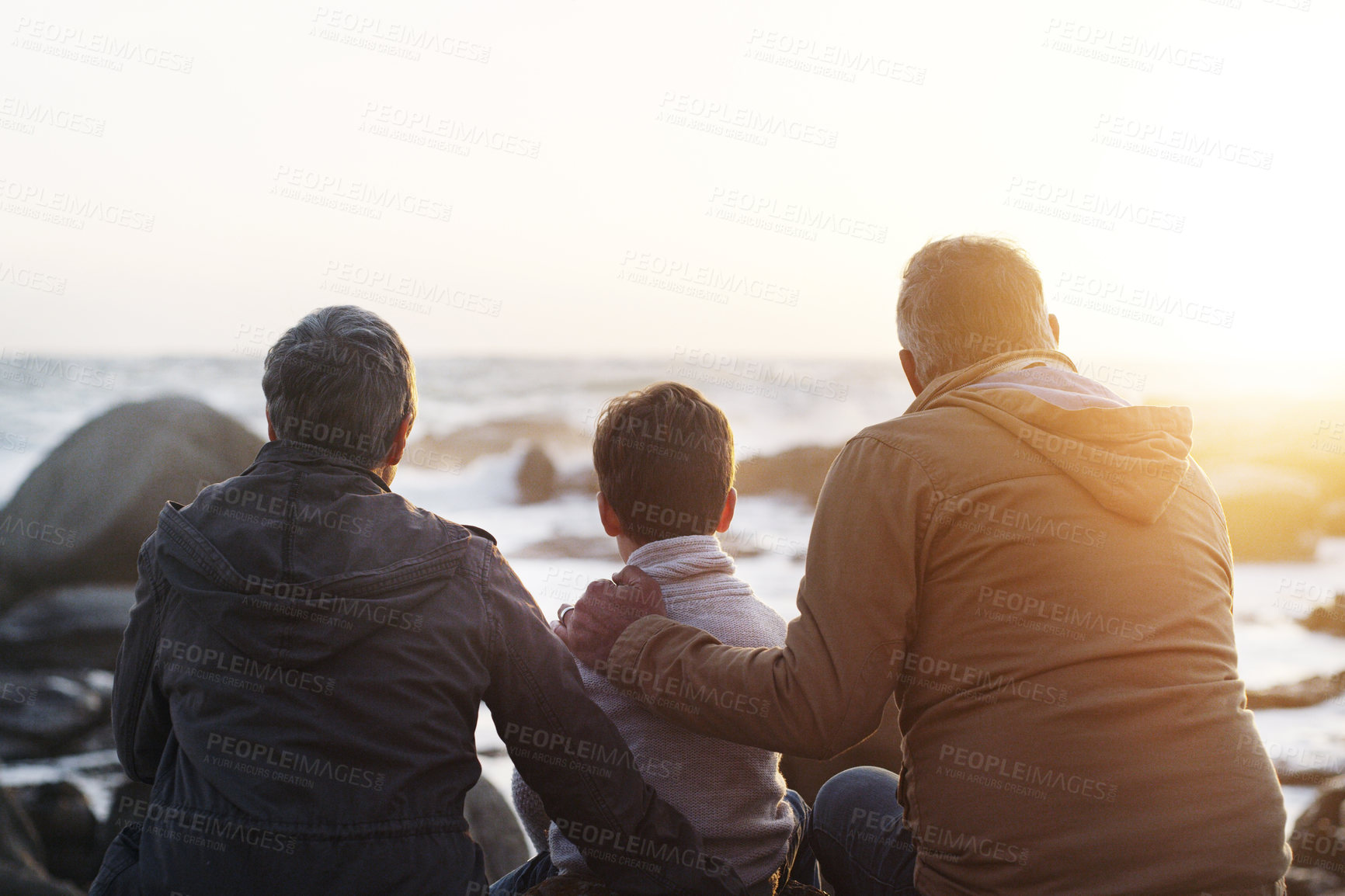 Buy stock photo Rearview shot a little boy and his grandparents relaxing at the beach