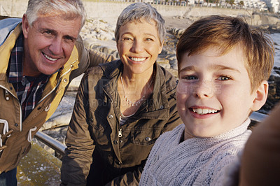 Buy stock photo Grandparents, child and portrait selfie on beach or social media post or bonding, profile picture or traveling. Man, woman and boy with smile for coastal vacation as family in California, sea or trip