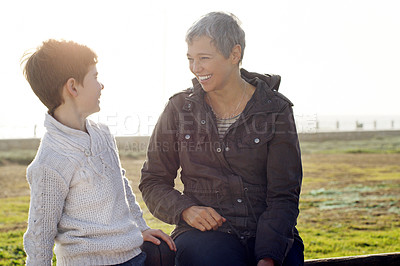 Buy stock photo Shot of an adorable little boy having a conversation with his grandmother outdoors