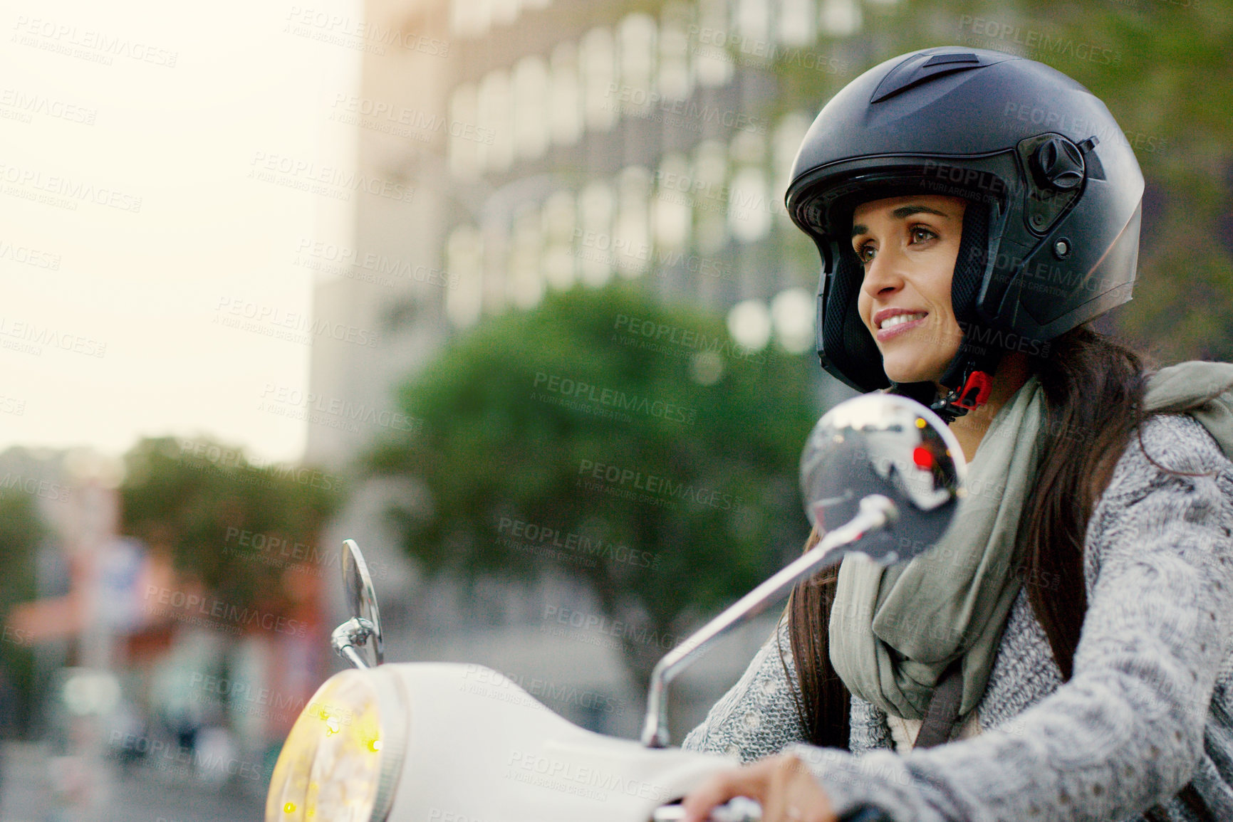 Buy stock photo Shot of an attractive young woman riding her scooter through the city