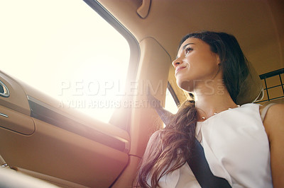 Buy stock photo Shot of an attractive young businesswoman sitting inside a car and looking out the window while travelling to work