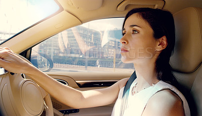 Buy stock photo Shot of an attractive young businesswoman driving her car to work