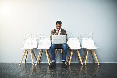 Buy stock photo Studio shot of a young businessman using a laptop while waiting against a gray background