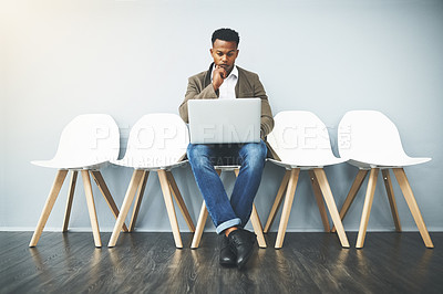 Buy stock photo Man, laptop and line for interview by wall in office with reading, thinking and research for job opportunity. Person, computer and queue with resume, email and onboarding at human resources agency