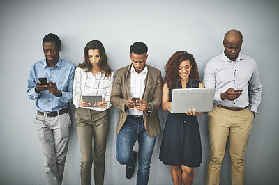Buy stock photo Studio shot of a group of businesspeople using their wireless devices while waiting in line