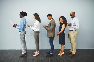 Buy stock photo Studio shot of a group of businesspeople waiting in a queue against a gray background