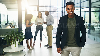 Buy stock photo Portrait of a young businessman standing in an office with his colleagues in the background