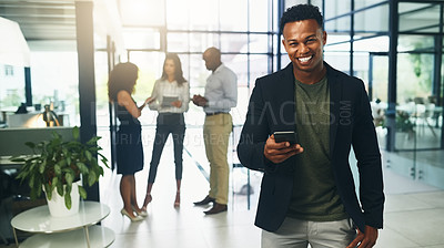 Buy stock photo Portrait of a young businessman using a cellphone in an office with his colleagues in the background