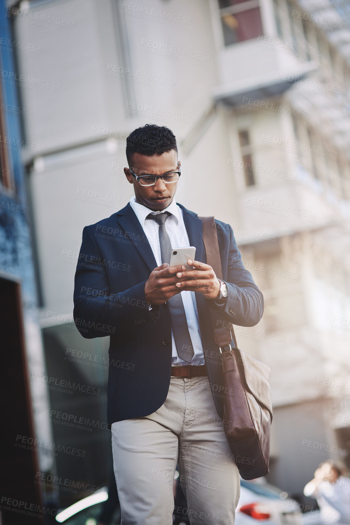 Buy stock photo Shot of a handsome young businessman using a cellphone in the city