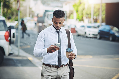 Buy stock photo Shot of a handsome young businessman using a cellphone in the city