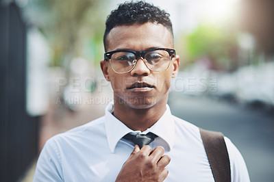 Buy stock photo Portrait of a handsome young businessman adjusting his tie while out in the city