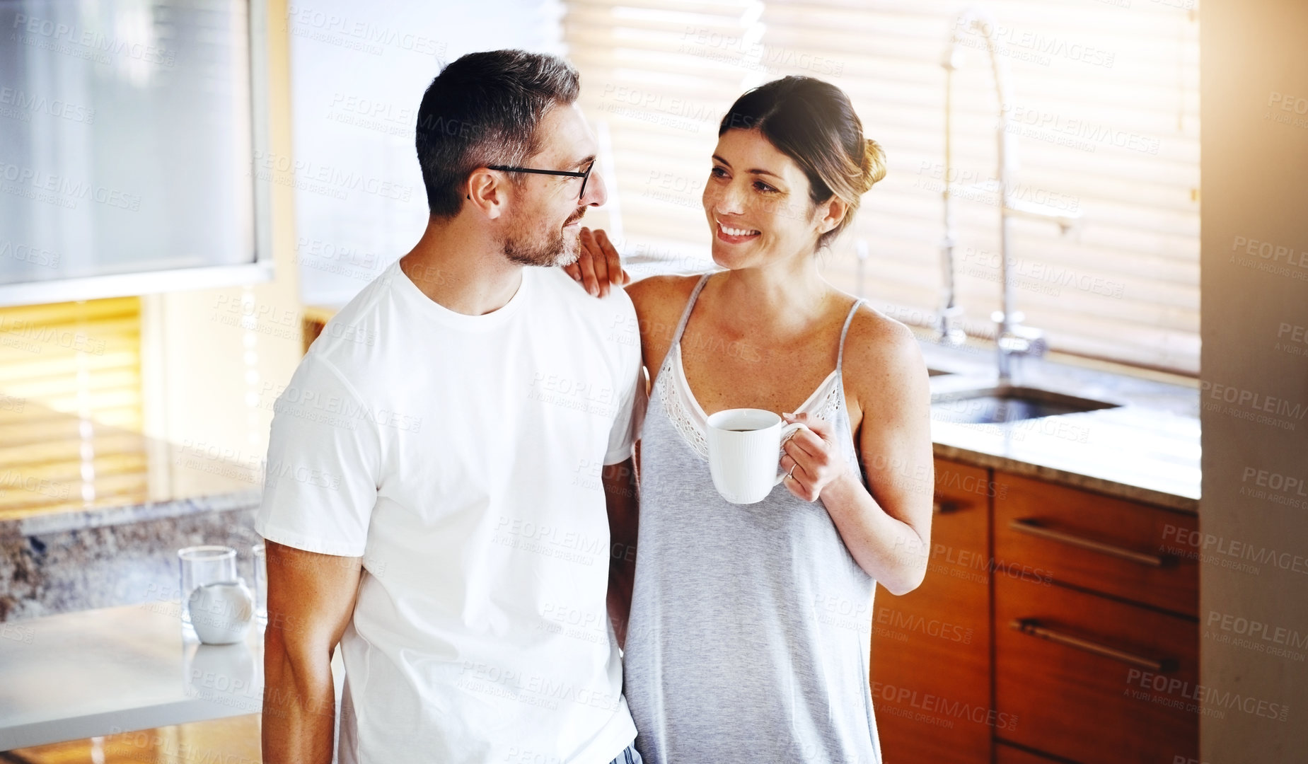 Buy stock photo Love, coffee and couple hug in a kitchen for morning, conversation and bonding at home together. Marriage, trust and people embrace with tea in house for speaking, security and romance on weekend