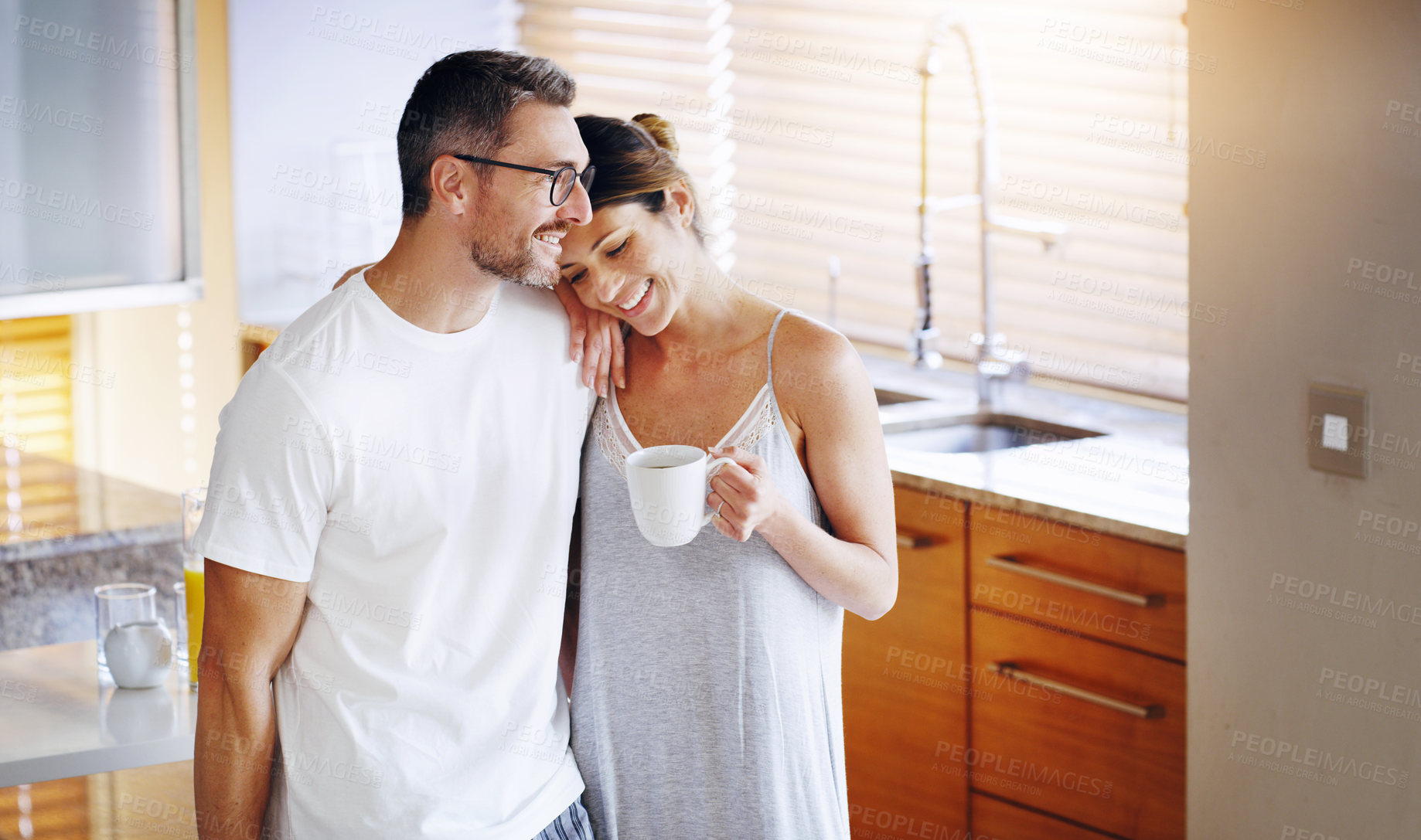 Buy stock photo Love, tea and couple hug in a kitchen for morning, conversation and bonding at home together. Marriage, trust and people embrace with coffee in house for speaking, security and romance on weekend