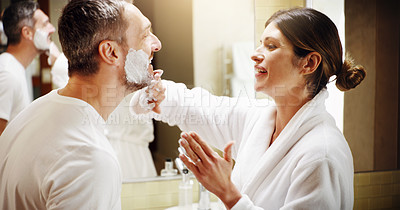 Buy stock photo Shot of a woman applying shaving cream to her husband's face in the bathroom at home